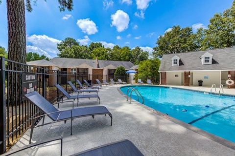 A pool area with sun loungers and a building in the background.