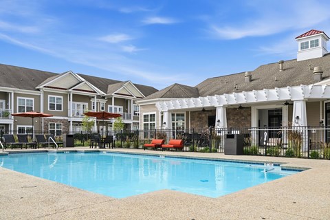 A swimming pool in front of a building with a white roof.