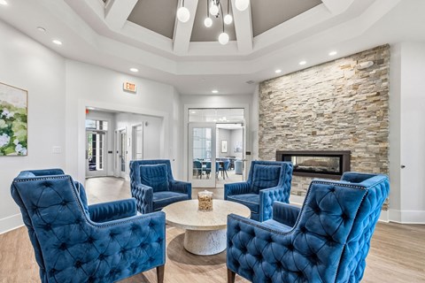 A living room with blue chairs and a stone fireplace.