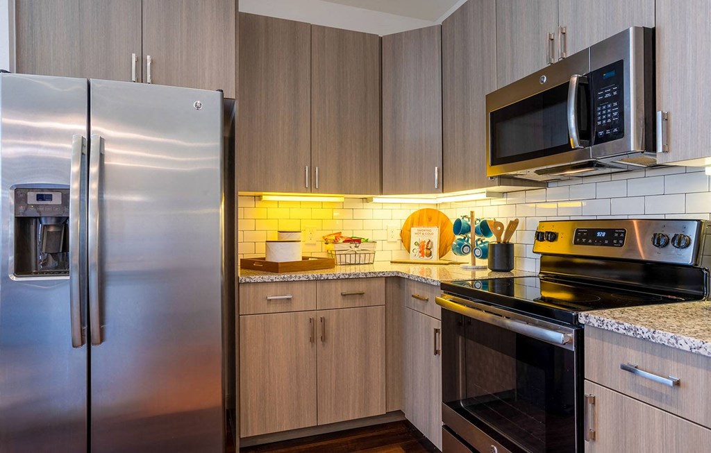 a kitchen with stainless steel appliances and wooden cabinets at The Parkway on Westlake, Texas, 77346