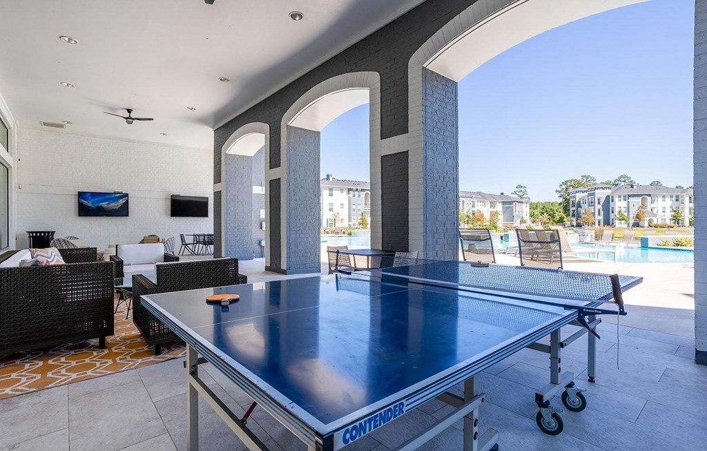 a ping pong table on a patio with a pool  at The Parkway on Westlake, Texas, 77346