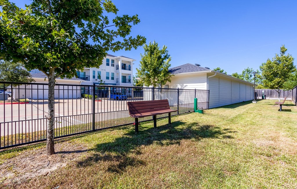a park bench sitting in front of a fence  at The Parkway on Westlake, Humble