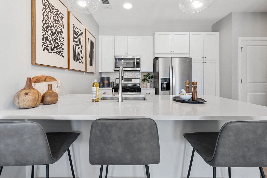 A modern kitchen with white cabinets and a large island with chairs at Madison Prickett Preserve, Pennsylvania, 19067