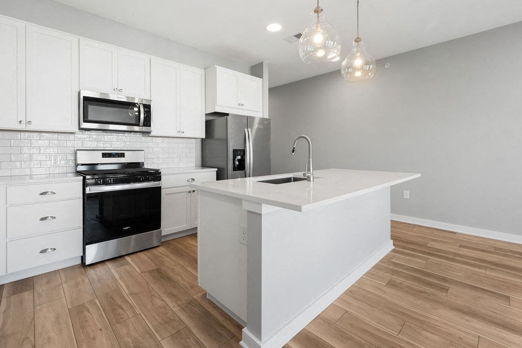 A kitchen with white cabinets and a wooden floor at Madison Prickett Preserve, Yardley