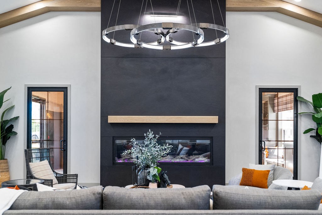A modern living room with a grey sofa, a fireplace, and a hanging light fixture at Madison Prickett Preserve, Yardley Pennsylvania