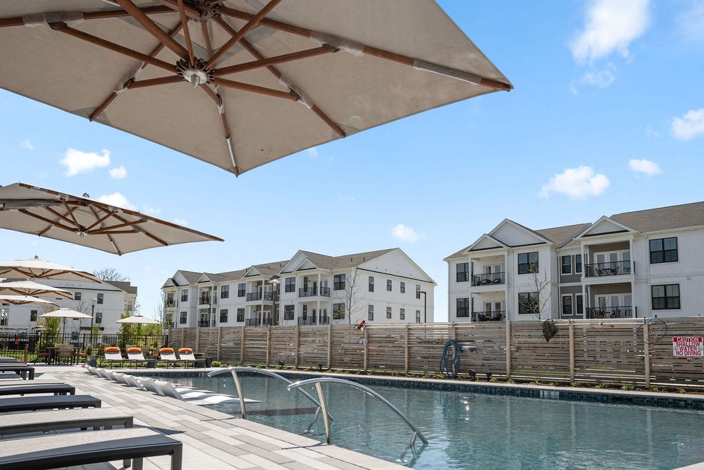 A pool area with sun umbrellas and apartment buildings in the background at Madison Prickett Preserve, Yardley Pennsylvania