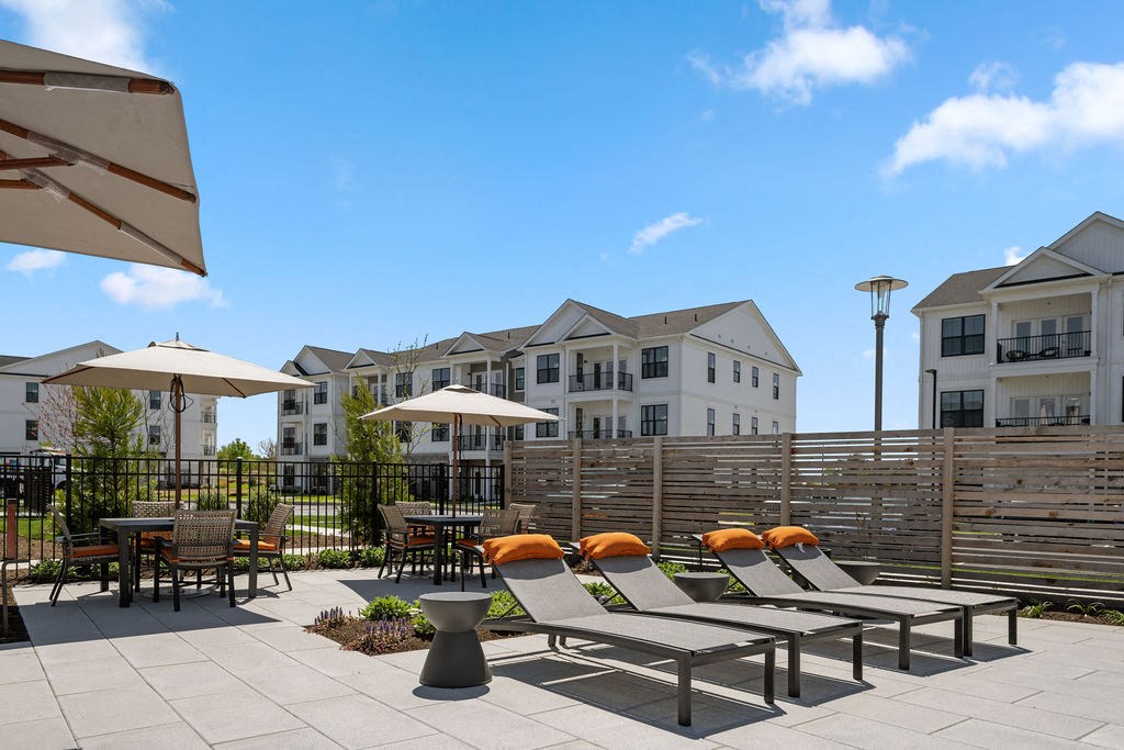 A patio with chairs and umbrellas in front of apartment buildings at Madison Prickett Preserve, Yardley