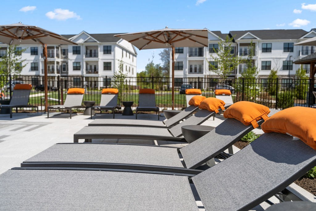 a patio with lounge chairs and umbrellas in front of an apartment building at Madison Prickett Preserve, Pennsylvania, 19067