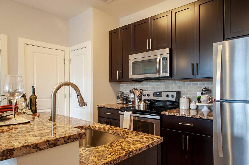 a kitchen with granite countertops and black cabinets  at Madison Providence, Pennsylvania