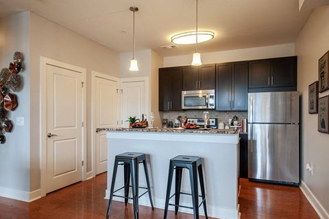 a kitchen with a bar and stools and a stainless steel refrigerator