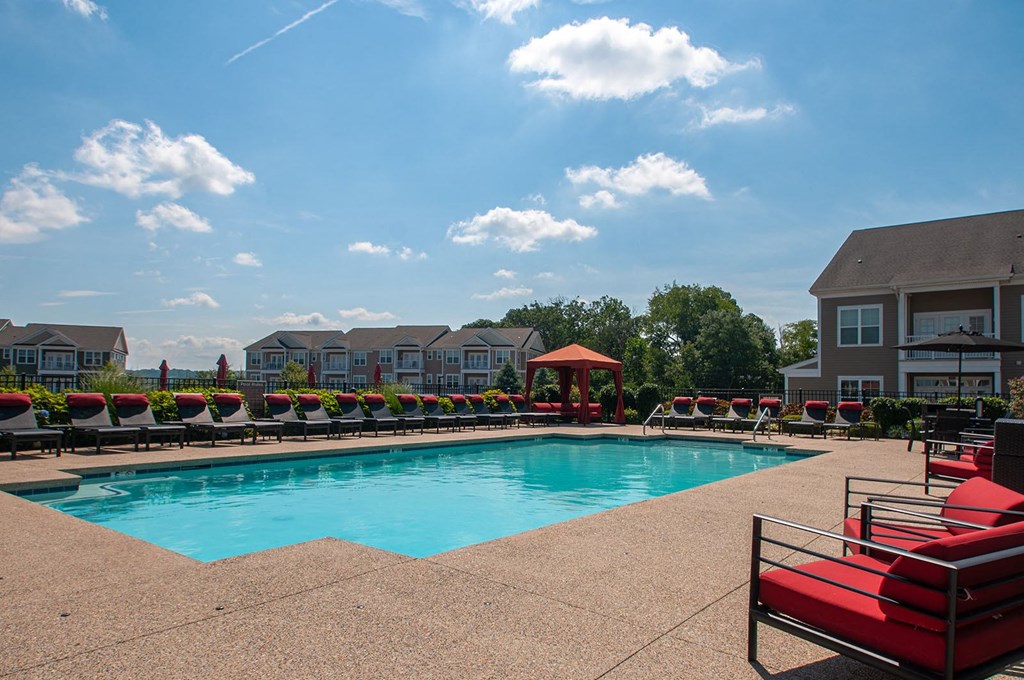 a swimming pool with lounge chairs and a gazebo with apartment buildings in the background  at Madison Providence, Collegeville, 19426