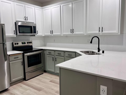 A kitchen with white cabinets and a stainless steel refrigerator.