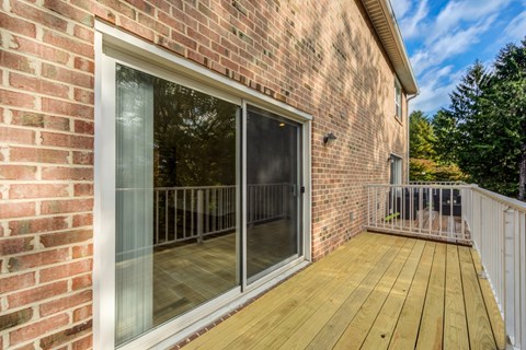 A brick house with a deck and sliding glass door.