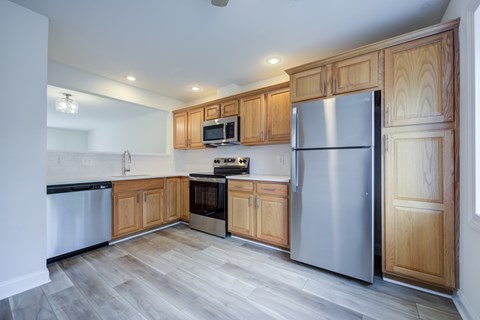 A kitchen with wooden cabinets and a stainless steel refrigerator.