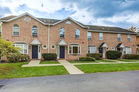 A red brick apartment building with a green lawn in front.