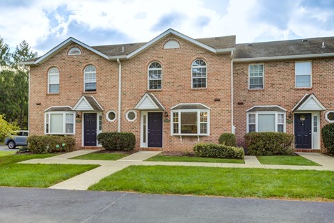 A red brick apartment building with a green lawn in front.