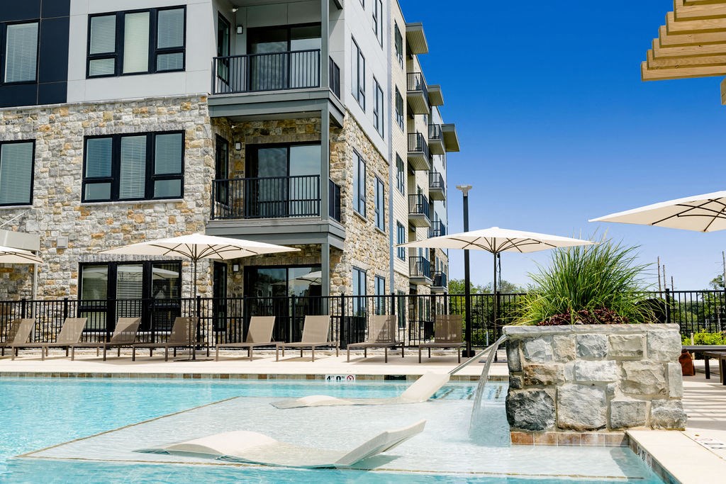 a swimming pool in front of a building with umbrellas at The Harrison, Newtown Square