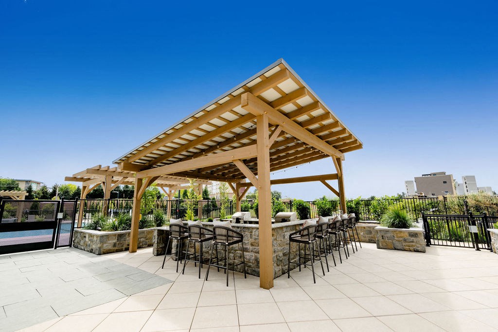 a patio with a table and chairs under a wooden pavilion at The Harrison, Newtown Square, PA, 19073