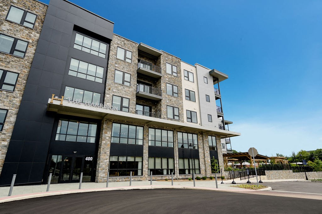 an exterior view of a large apartment building with a parking lot at The Harrison, Newtown Square, 19073