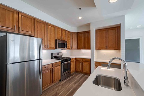 A kitchen with wooden cabinets and a stainless steel refrigerator.