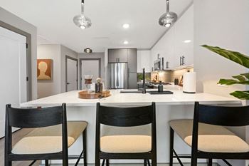 an open kitchen with an island and three chairs at Madison West Elm, Conshohocken, PA