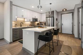 A modern kitchen with a center island and bar stools at Madison West Elm, Conshohocken, PA 19428