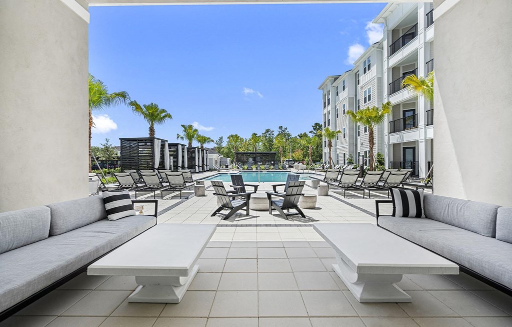 a pool with lounge chairs and tables in front of an apartment building at Madison Waterford Lakes, Orlando, 32826