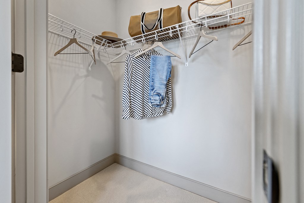 a walk in closet with white walls and a white coat rack with clothes on it at The Harrison, Newtown Square, PA