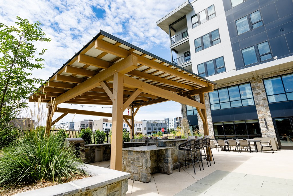 an outdoor patio with a stone table and chairs and a wooden pergola at The Harrison, Newtown Square, PA, 19073
