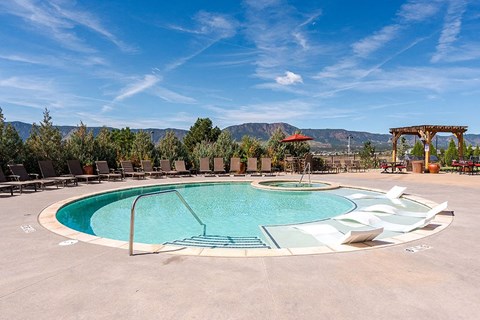 A large outdoor swimming pool surrounded by lounge chairs and trees at Vistas at Jackson Creek, Monument