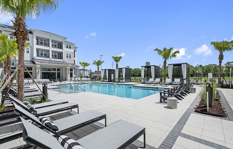 a swimming pool with lounge chairs and a building in the background at Madison Waterford Lakes, Orlando, 32826
