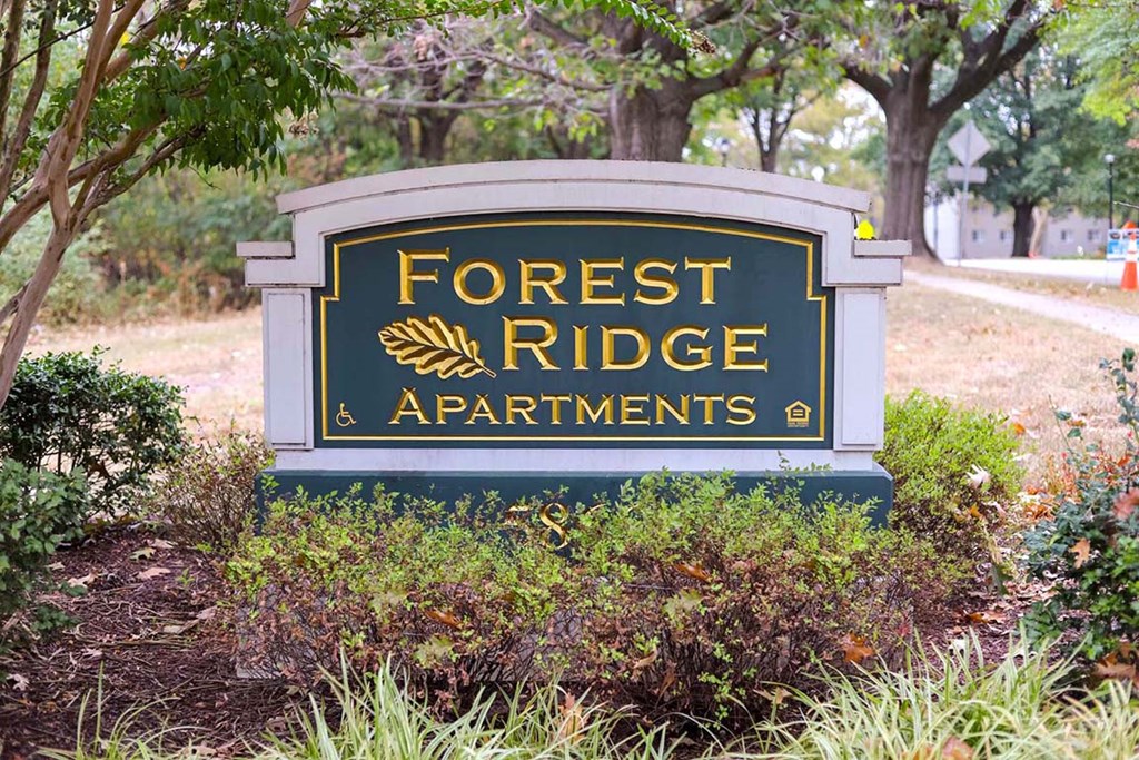 a sign that says forest apartments  in front of trees