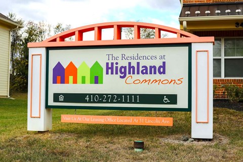 A sign for The Residences at Highland Commons with a phone number and an arrow pointing to a leasing office.