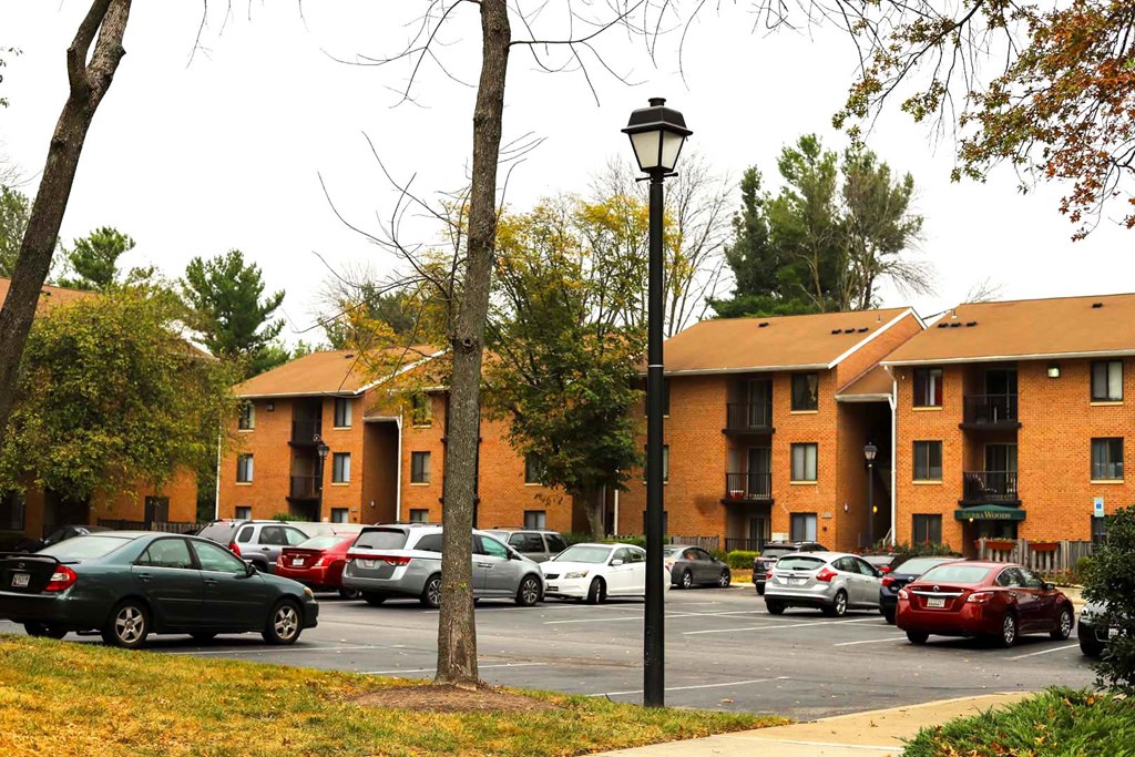 a parking lot filled with cars in front of an apartment building