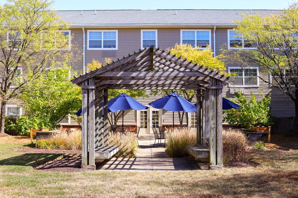 a wooden gazebo with blue umbrellas in front of a house