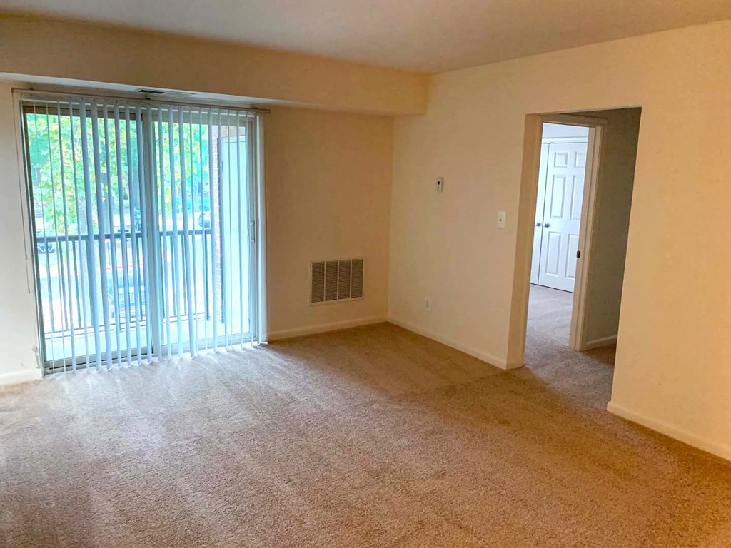 an empty living room with a large window and a door