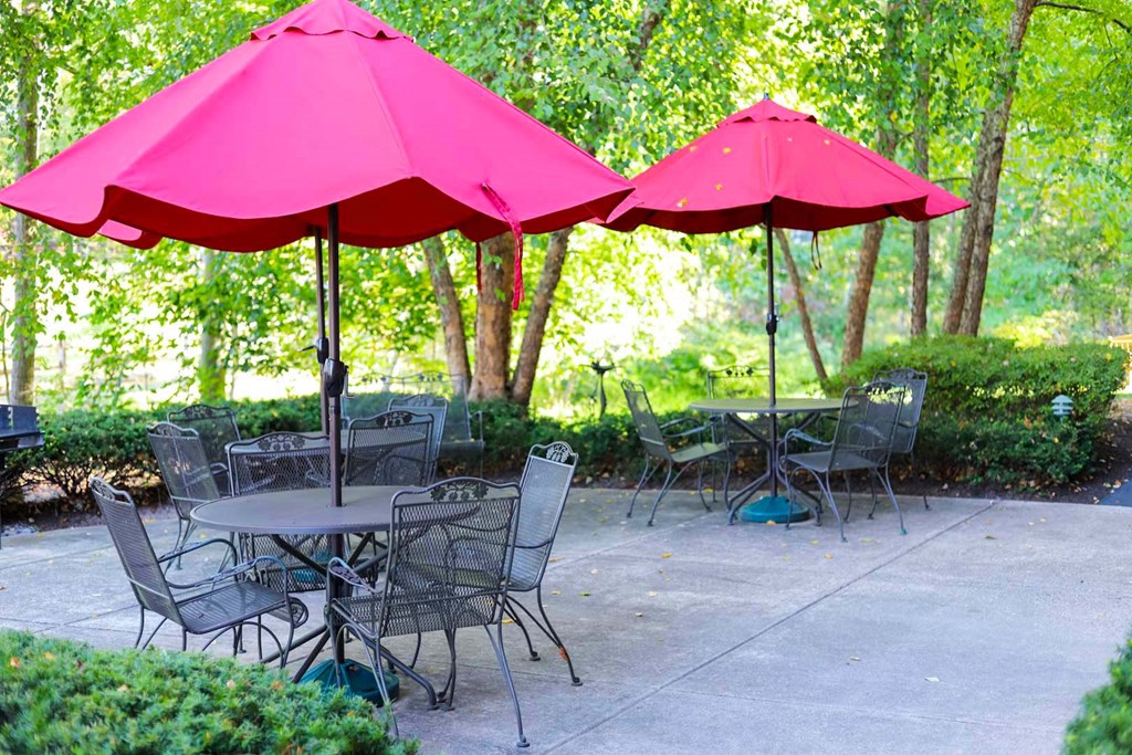 two pink umbrellas over tables and chairs on a patio