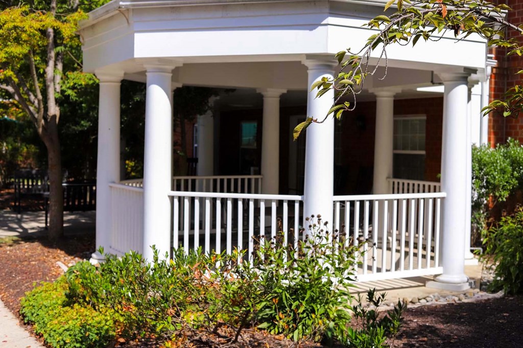 the front porch of a house with columns and a porch swing