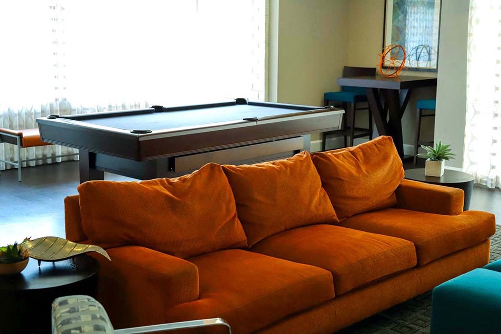 a pool table in a living room with a orange couch