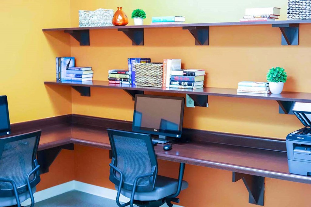 a computer desk with two chairs and a monitor