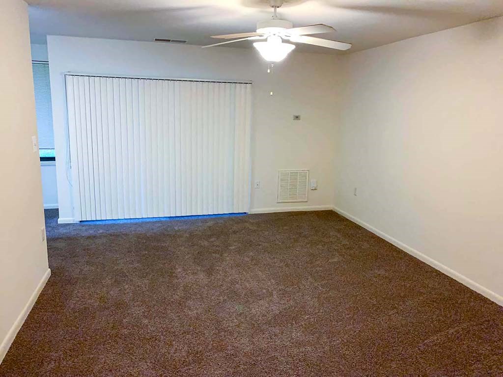 an empty room with a ceiling fan and a window