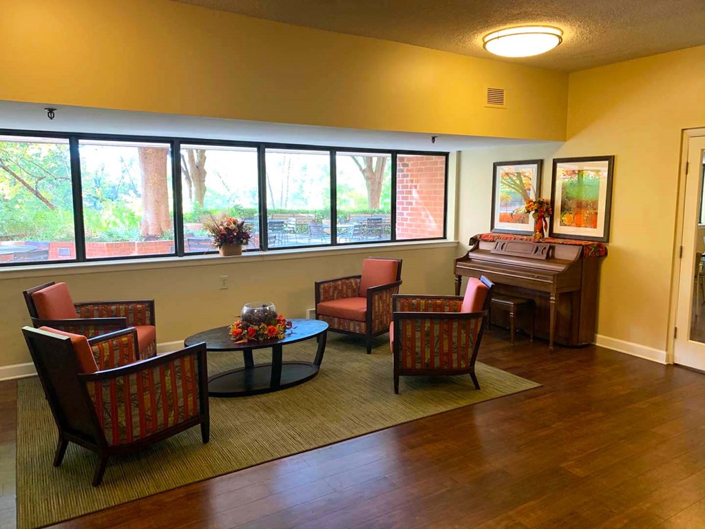a living room with chairs and a piano