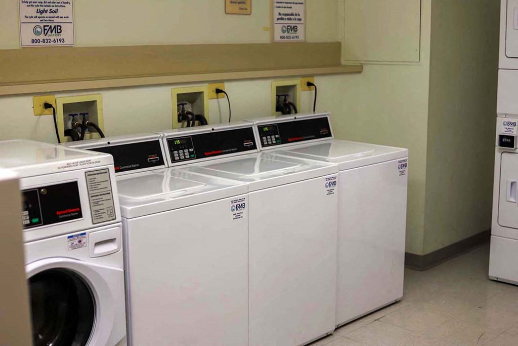 a row of washers and dryers in a laundry room