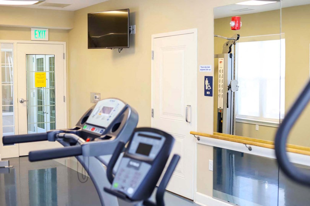a gym with two machines and a television on the wall