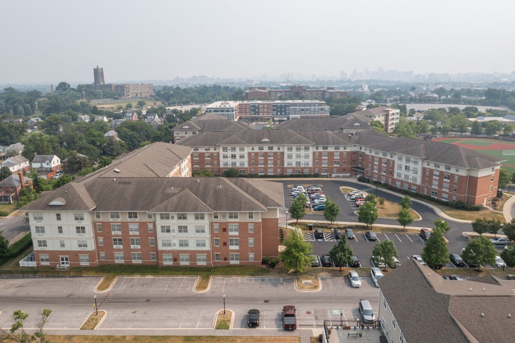 a large brick building with a parking lot in front of it and a city in the background