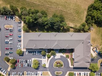 arial view of a building with a parking lot and a grassy hill in the background