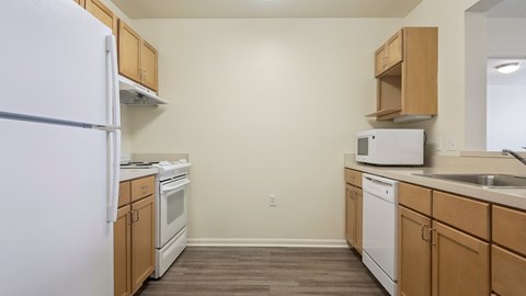 A kitchen with white appliances and wooden cabinets.