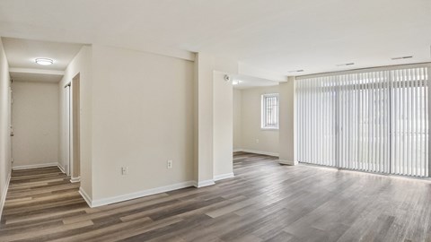 A spacious room with wooden flooring and white walls.
