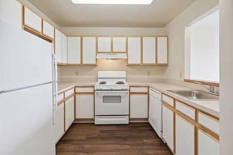 A kitchen with white appliances and wooden cabinets.