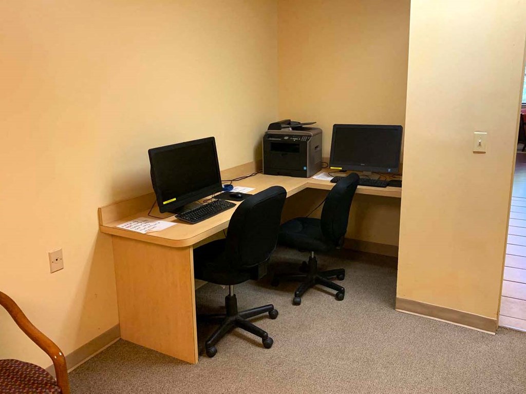 a desk with two computers and a chair in a room